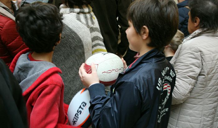 Due bambini attendono che i loro palloni vengano autografati