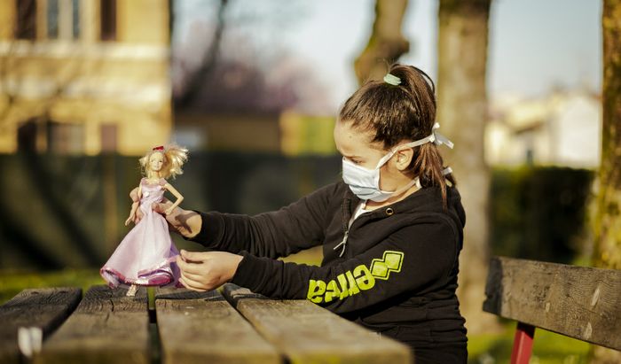 Una bambina gioca in giardino con la sua bambola