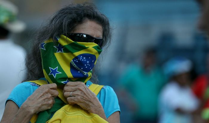 Una donna si protegge bocca e naso con la bandiera del Brasile