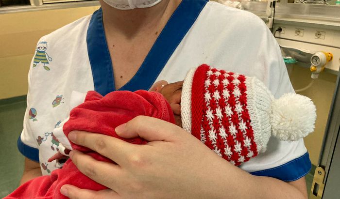 Un'infermiera della Pat.Neonatale veste un bimbo per il Natale