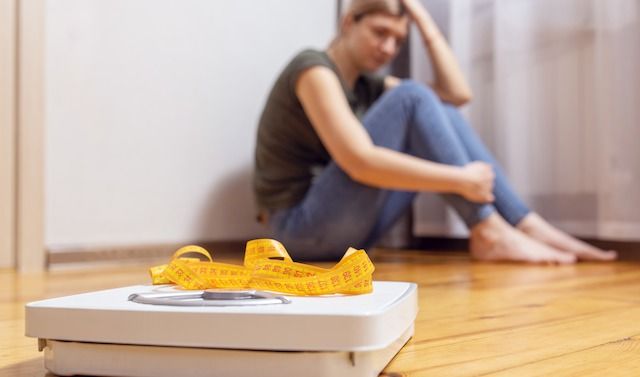 White scale and depression, upset and sad woman with measuring tape on wooden floor.