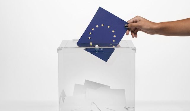 Person-putting-european-union-flag-card-into-ballot-box

